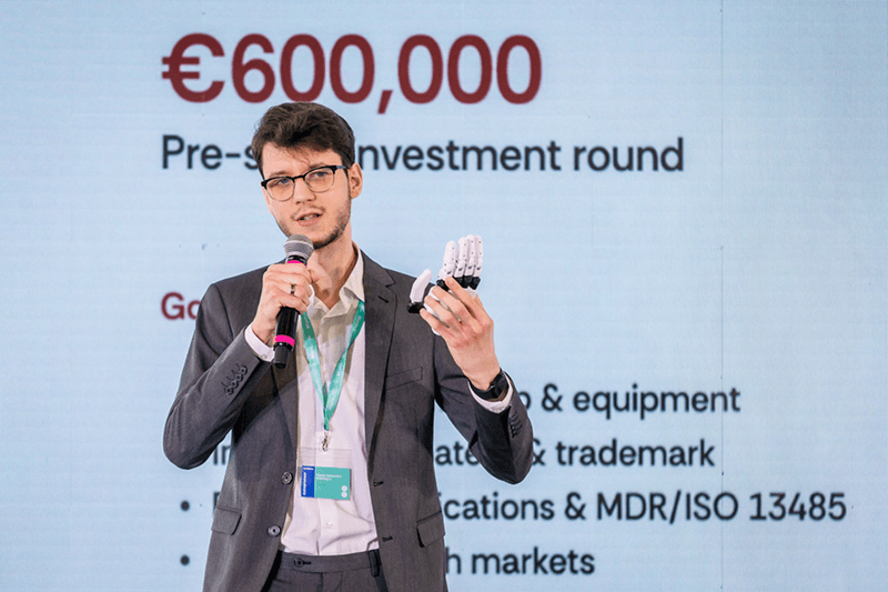 Origin BCI founder holding the bionic hand during the re:Mark 2026 pitch